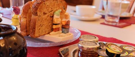 Una mesa con pan, mermeladas y una taza.