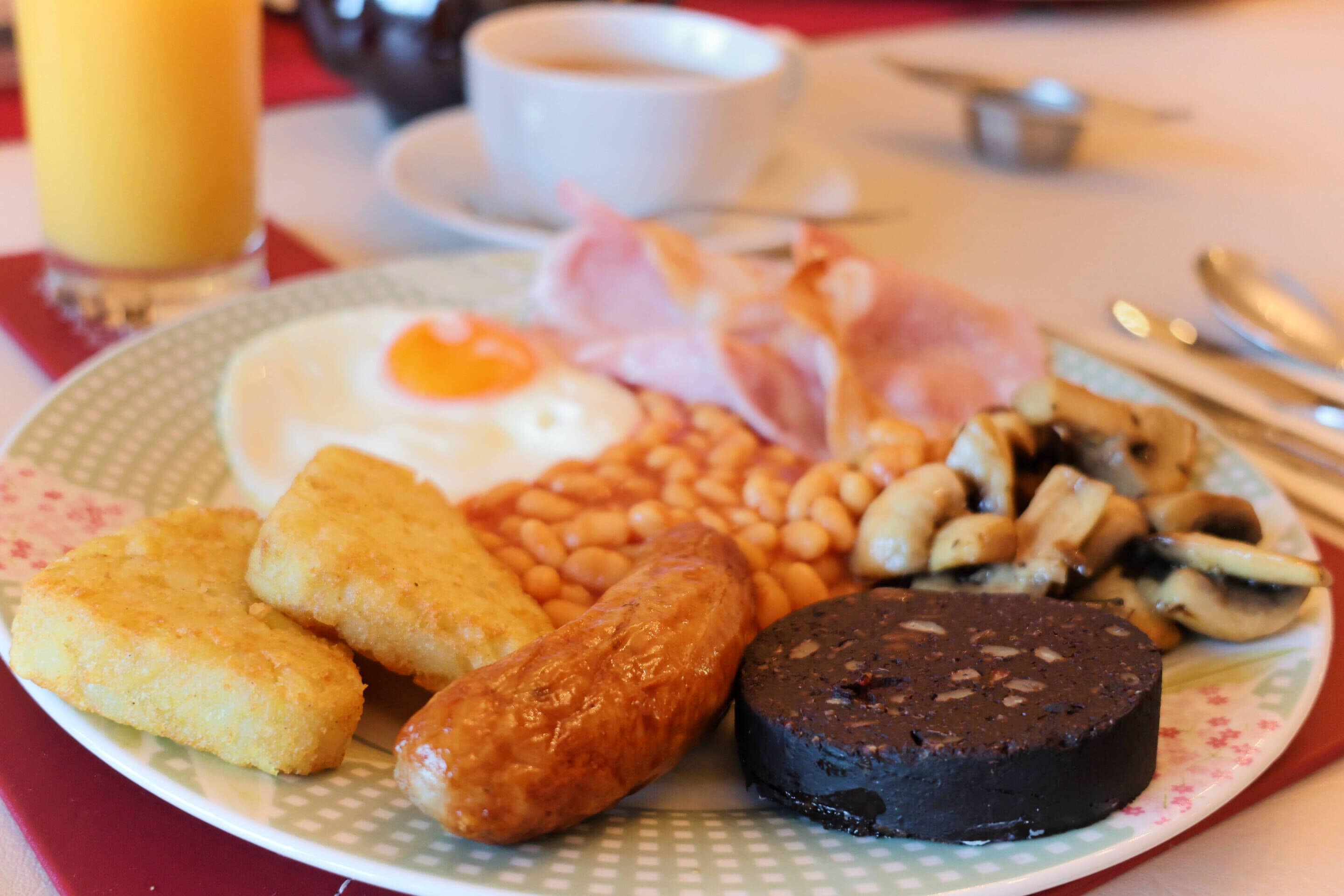 Une assiette de nourriture pour le petit-déjeuner comprenant des œufs, des saucisses, des haricots et des toasts.