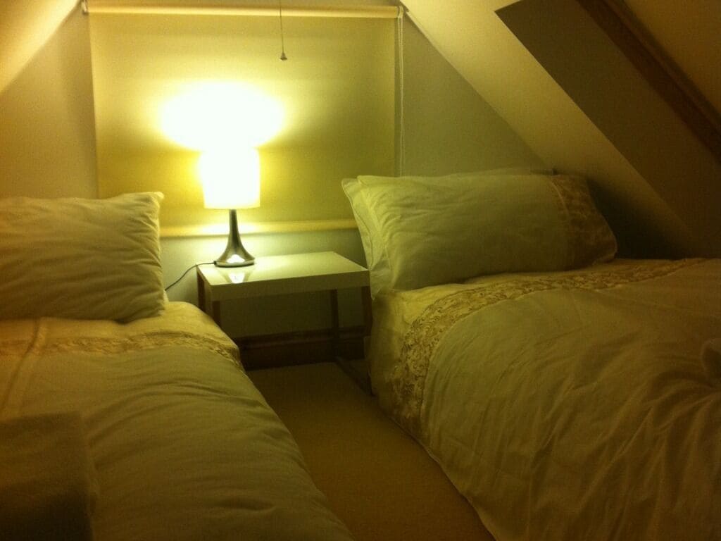 A small, dimly lit room with two beds and a nightstand.