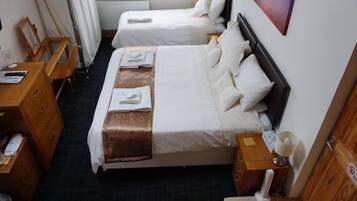 Een hotelkamer met twee enkele bedden, een houten dressoir, een bureau en een raam met gordijnen.