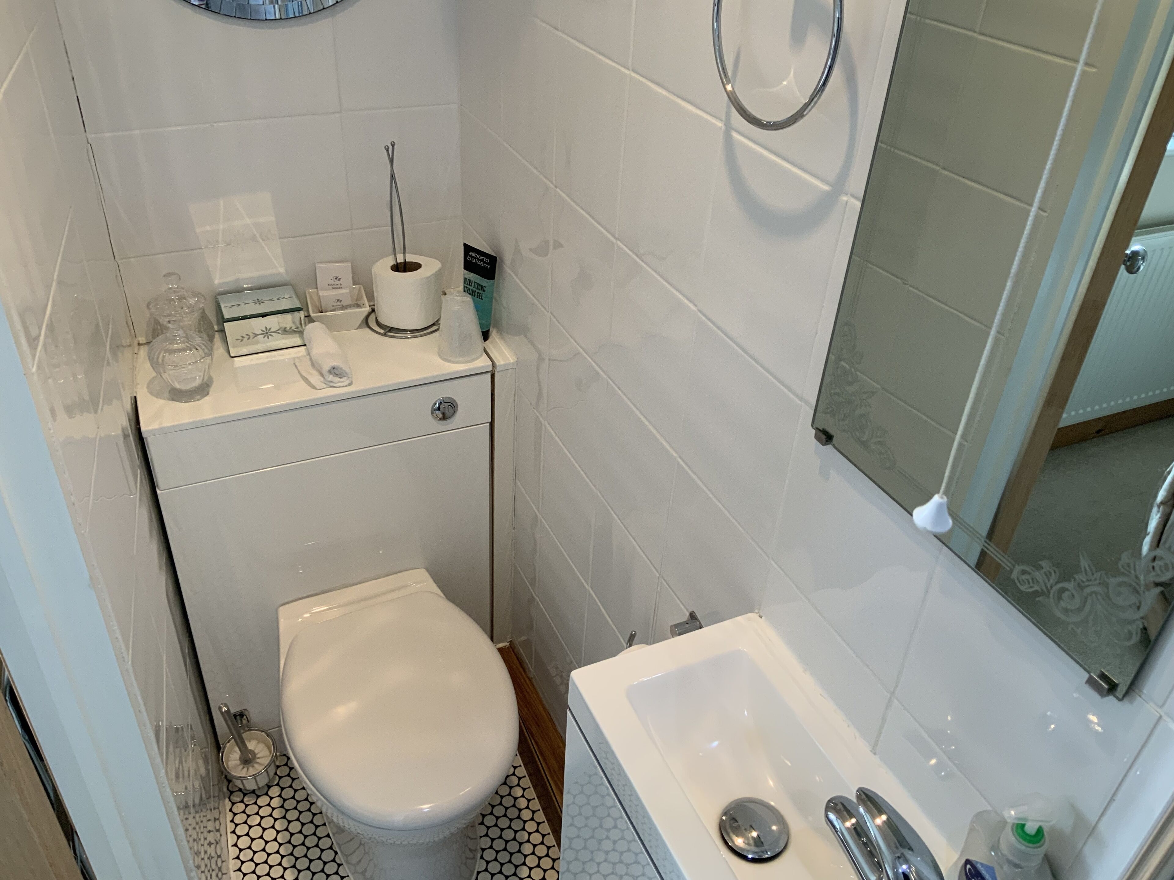 A compact bathroom with a toilet, sink, and a mirror.