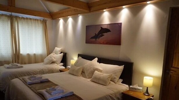 Habitación de hotel con dos camas, un cuadro en la pared y una lámpara en la mesita de noche.
