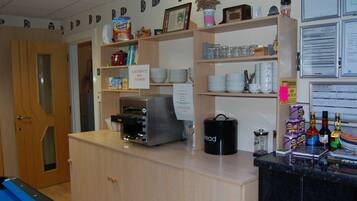 Una zona de cocina con un tostador, una cafetera y varios utensilios de cocina en estantes.