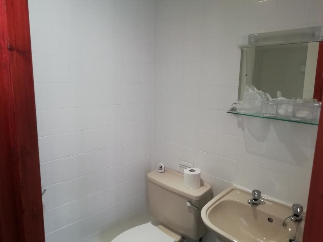 A small bathroom with a toilet, sink, and a glass shelf above the sink.