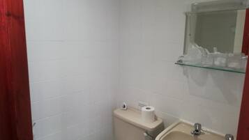 A small bathroom with a toilet, sink, and a glass shelf above the sink.