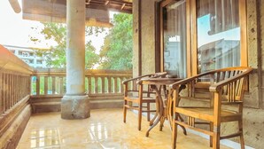 A wooden balcony with a tiled floor, a wooden table, and two wooden chairs. - Villa Happy (Kedonganan)