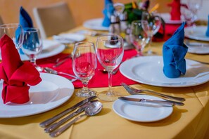 Une table mise pour le repas, avec des assiettes, des couverts et des verres à vin.
