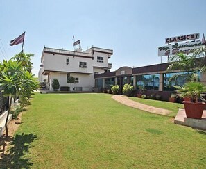 Um hotel com um gramado bem cuidado, um caminho que leva à entrada e uma placa indicando ser um hotel Classic.