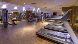 A modern gym with multiple treadmills, weight machines, and a mirrored wall. - Pride Plaza Hotel, Kolkata (Barasat)