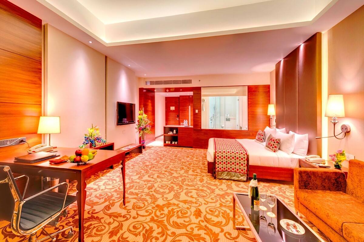 A hotel room with a bed, desk, chair, TV, and a bathroom visible through an open door.
