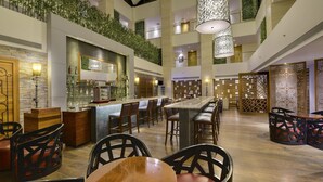 A spacious hotel lobby with a long reception desk, multiple seating areas, and a high ceiling with hanging lights. - Pride Plaza Hotel, Kolkata (Barasat)