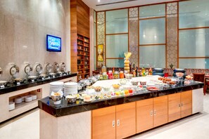 A buffet setup with various food items and a television screen on the wall.