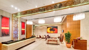 A modern hotel lobby with a reception desk, seating area, and artwork on the walls. - Pride Plaza Hotel, Kolkata (Barasat)