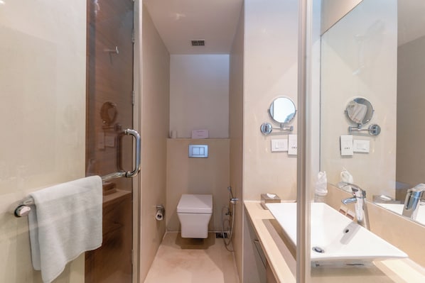 Un baño moderno con cabina de ducha de vidrio, inodoro blanco y lavabo con espejo.