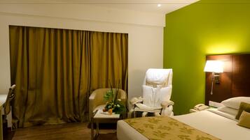 Une chambre d’hôtel avec un lit, une chaise, un bureau, une lampe et un rideau.