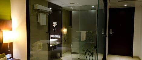 A modern bathroom with a glass-enclosed shower, a standalone sink, and a large bathtub.