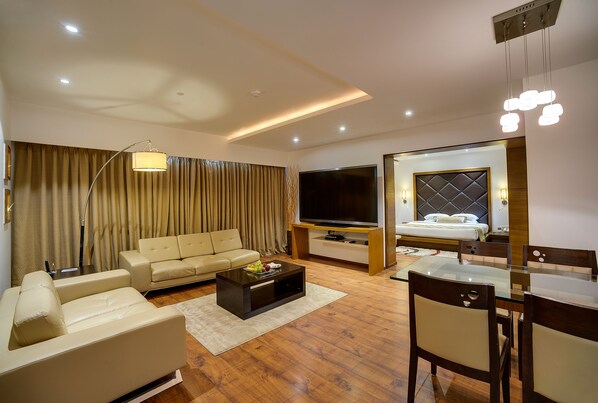 A modern living room with a sofa, TV, and dining area. - Ramee Grand Hotel and Spa, Pune (Pune)