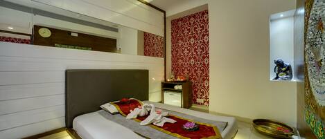 A modern hotel room with a neatly made bed, a bedside table with a lamp, and a decorative wall panel.