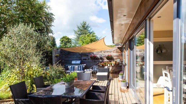 An outdoor patio with wicker furniture, a glass table, and a barbecue grill. - Birch House B&B (Weymouth)