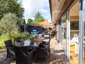An outdoor patio with wicker furniture, a glass table, and a barbecue grill. - Birch House B&B (Weymouth)