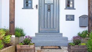 A white building with a blue door, two windows, and a sign reading "BIRCH HOUSE 31". - Birch House B&B (Weymouth)