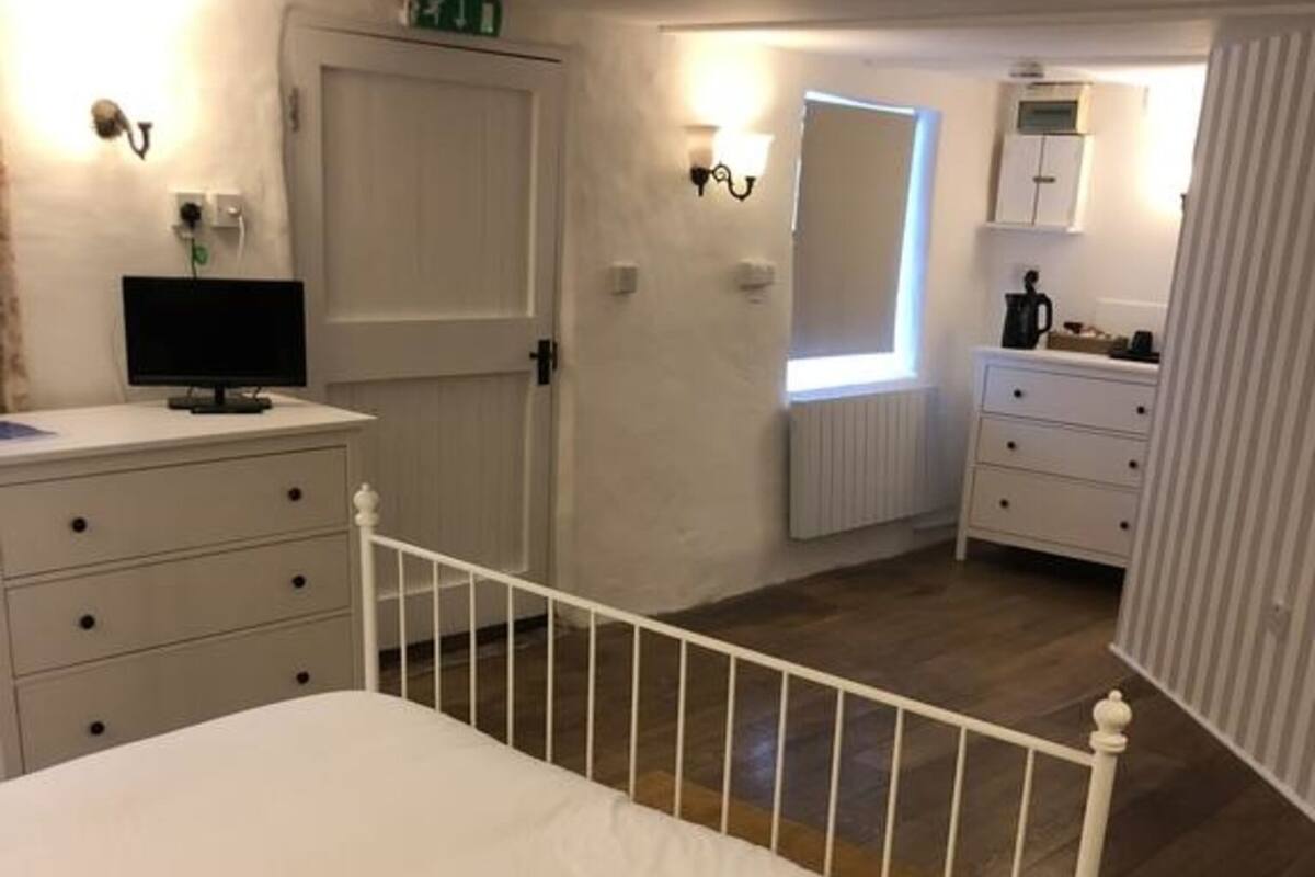 A bedroom with a single bed, a dresser, a desk with a computer, and a window.
