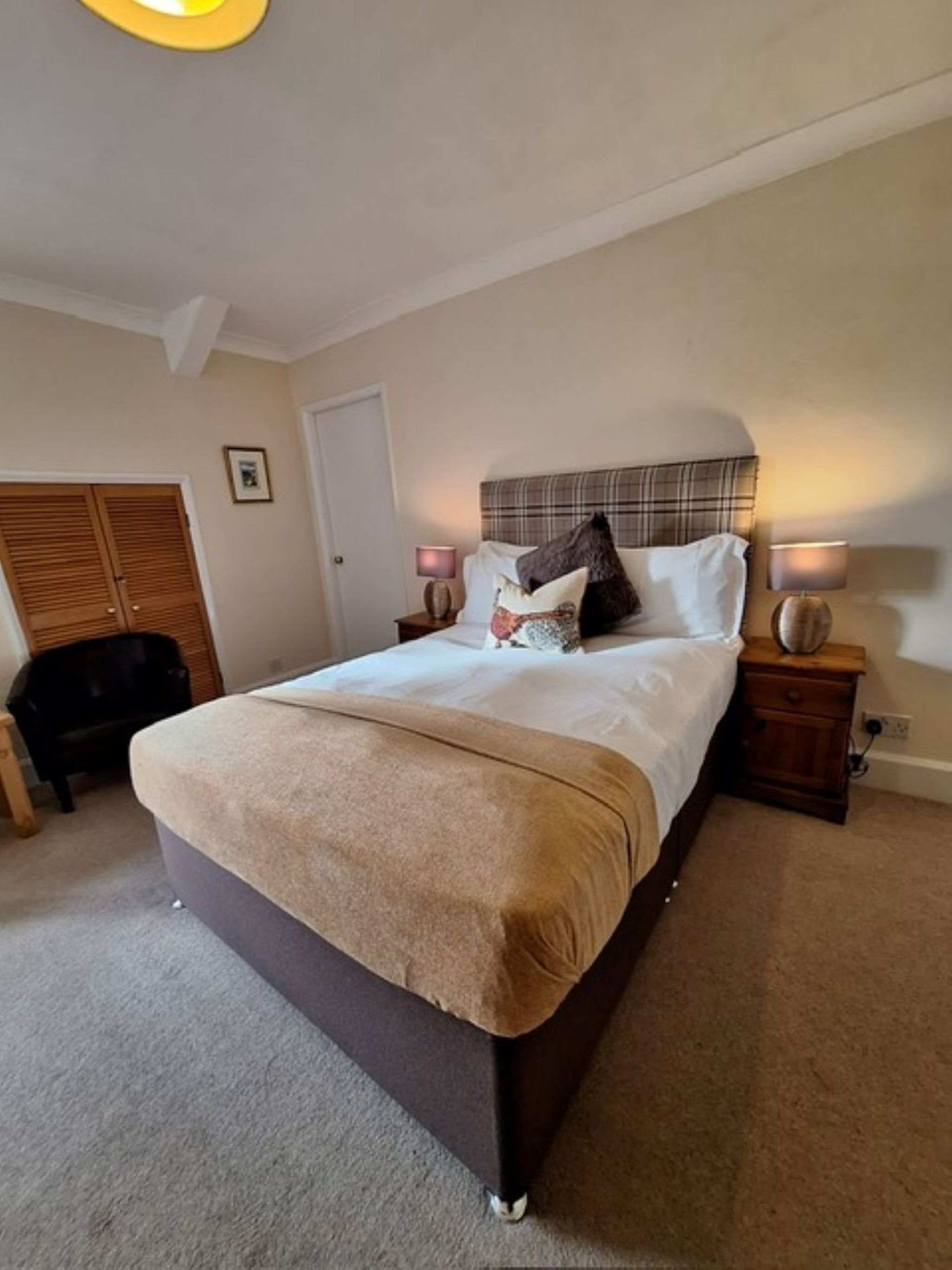 A bedroom with a bed, bedside tables, a wardrobe, and a door.