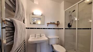 Un baño moderno con cabina de ducha de vidrio, un lavabo blanco y un inodoro.
