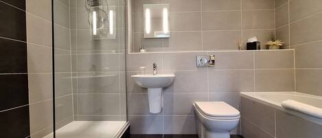 A modern bathroom with a glass-enclosed shower, a pedestal sink, a toilet, and a bathtub.