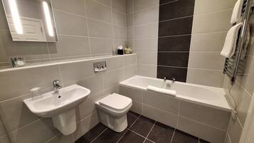 Un baño moderno con dos lavamanos, un inodoro y una bañera.