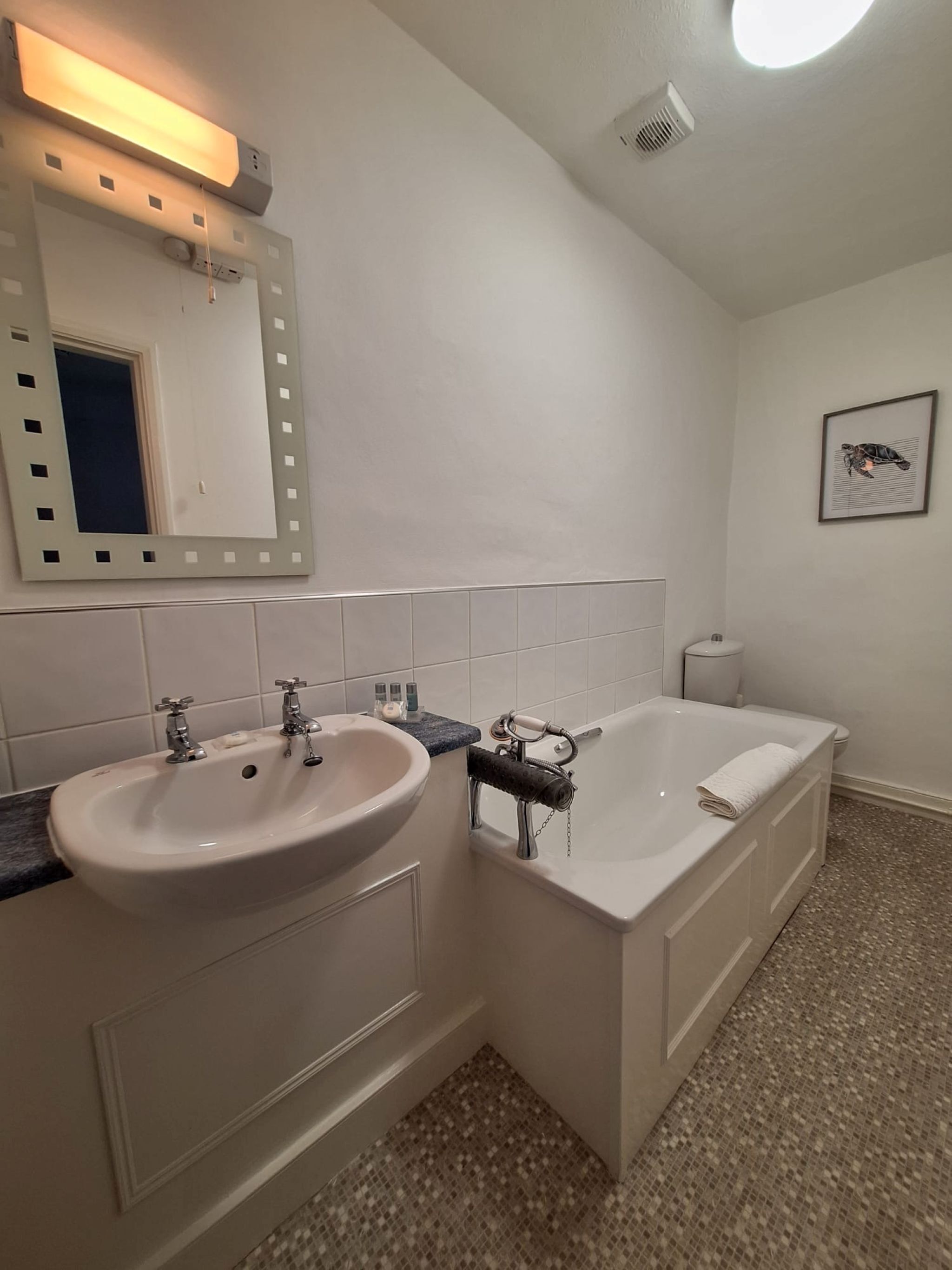 Un baño con dos lavamanos, una bañera, un espejo grande y un inodoro.
