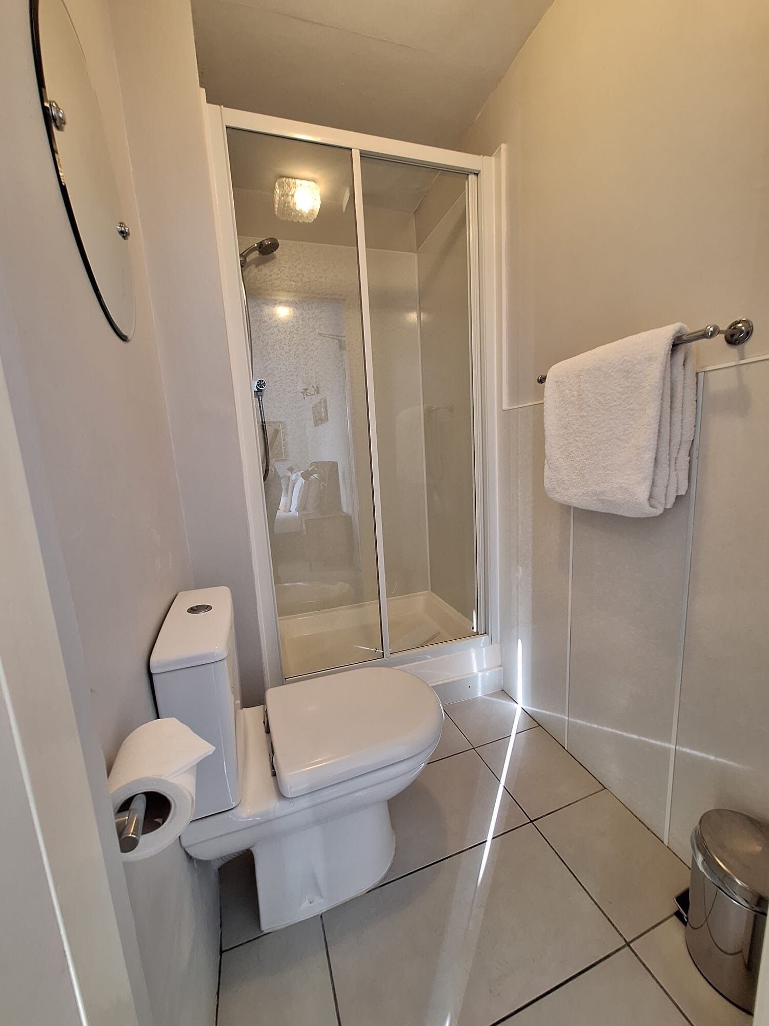 Ein modernes Badezimmer mit Toilette, Duschkabine und Handtuchhalter.