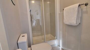 Ein modernes Badezimmer mit Toilette, Duschkabine und Handtuchhalter.