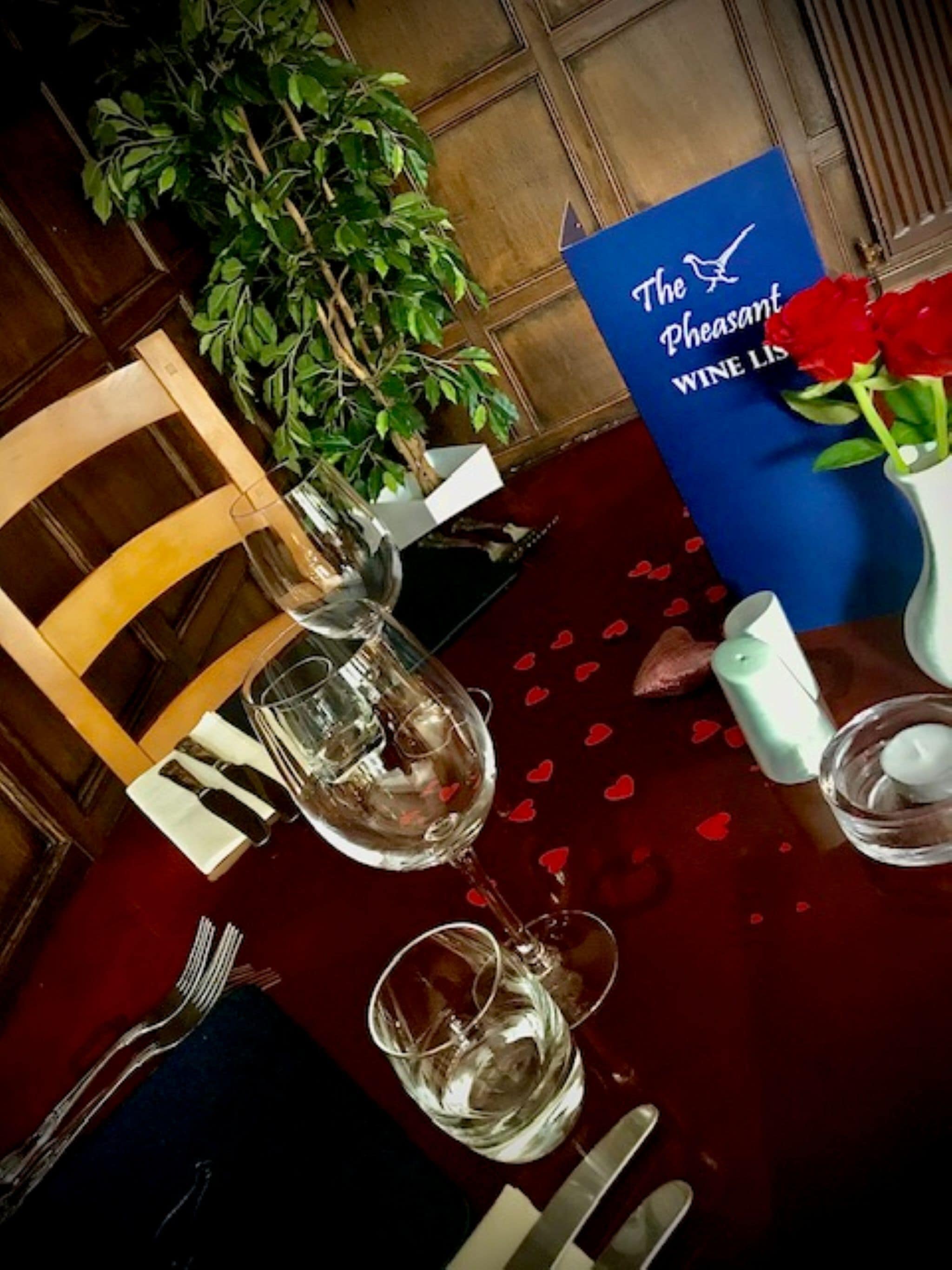 A table set for a meal with a wine glass, a candle, and a vase with flowers.