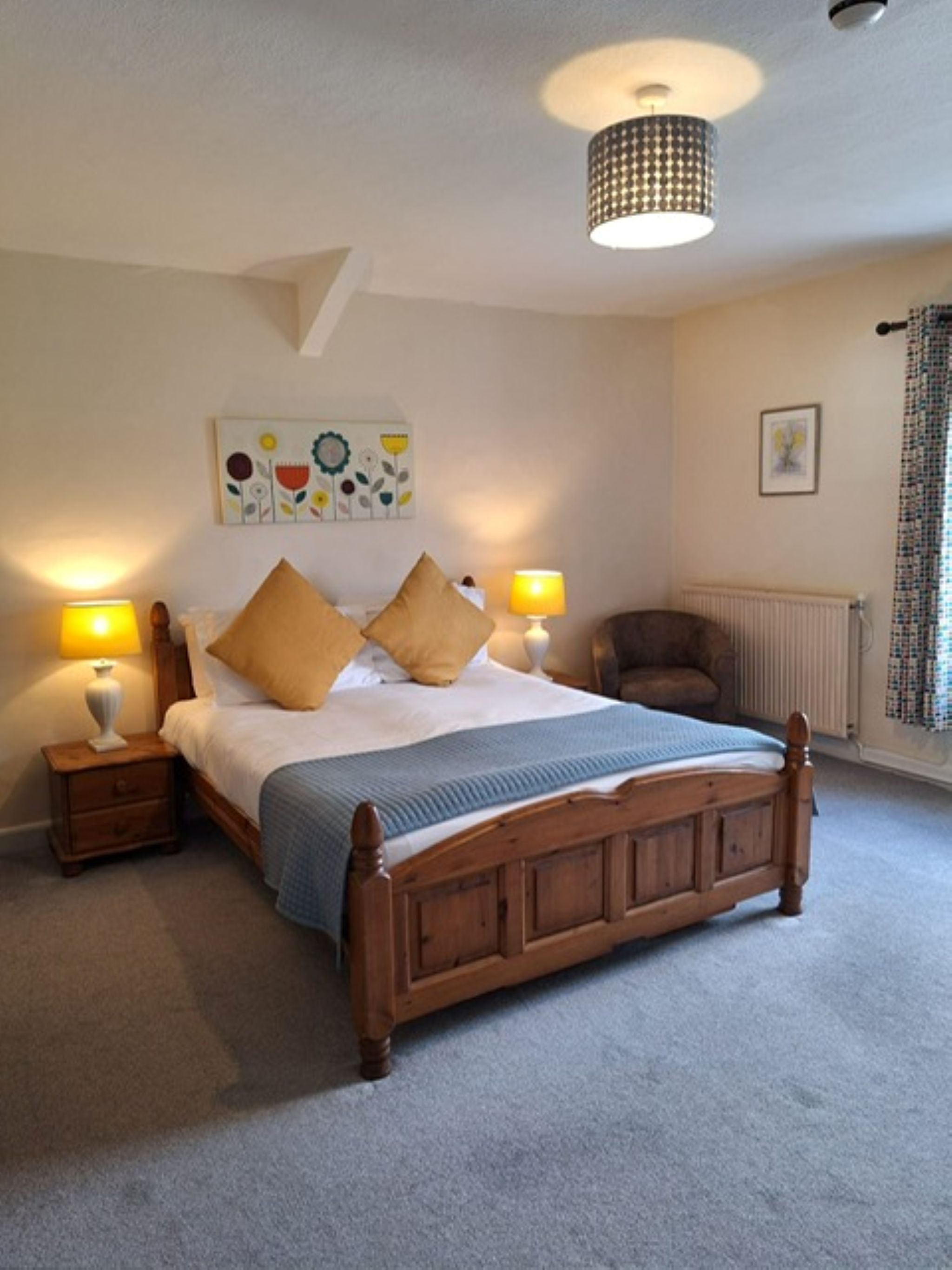 Une chambre à coucher avec un lit en bois, deux tables de chevet avec des lampes, un radiateur et un luminaire au plafond.
