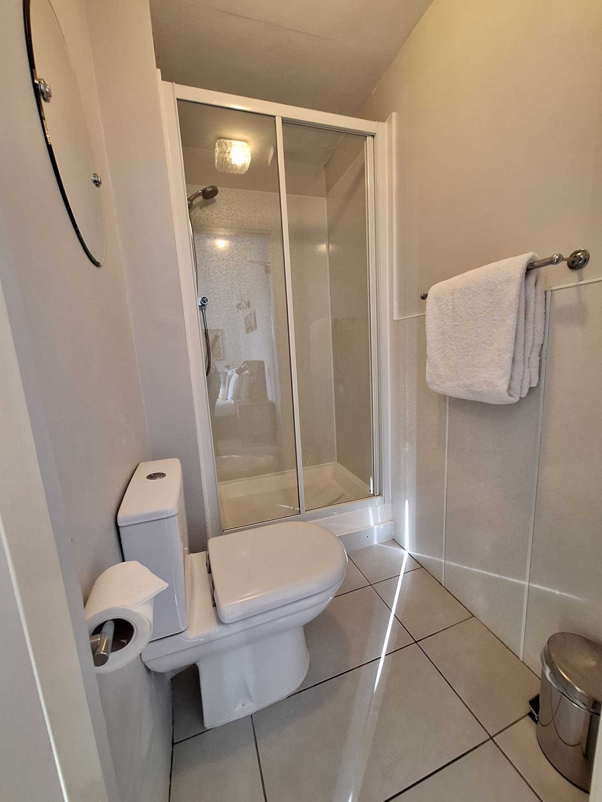 Un baño moderno con inodoro, cabina de ducha y barra para toallas.
