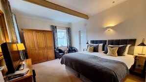 Une chambre avec un grand lit, une armoire, un bureau avec une lampe et une chaise.