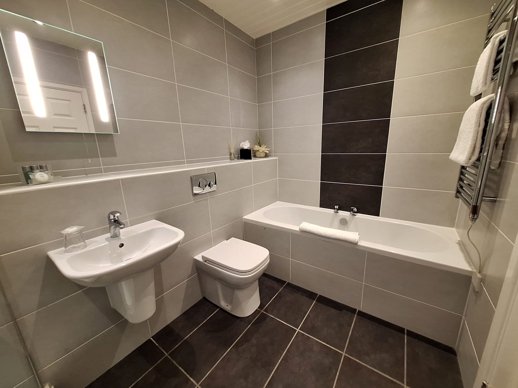 A modern bathroom with two sinks, a toilet, and a bathtub.