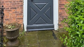 A dark grey door with a diamond pattern, flanked by two black wall-mounted lamps. A sign above the door reads "PICKMERE HOUSE". - Pickmere Country House (Knutsford)