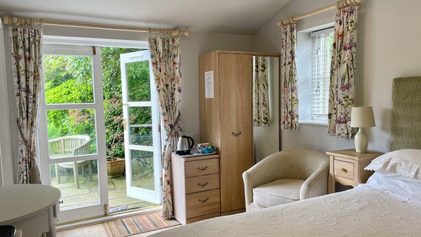 A bedroom with a bed, a wooden wardrobe, a desk, a chair, and a window with curtains. - Pickmere Country House (Knutsford)