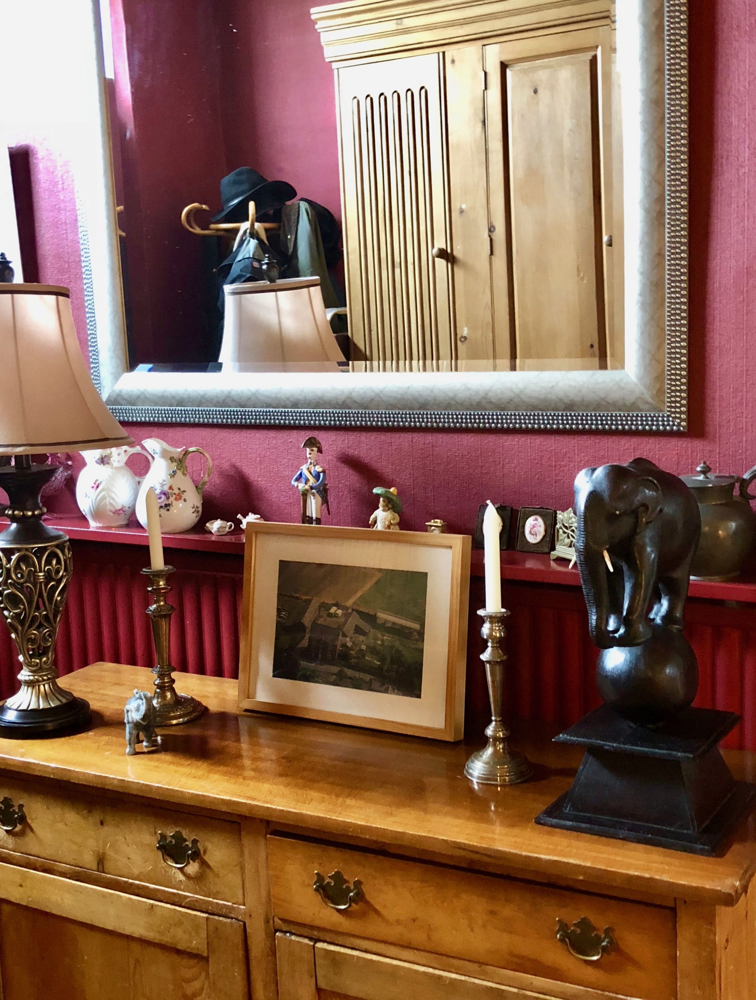 A wooden dresser with drawers, a framed photograph, a candlestick, and a statue.