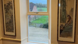 A room with a window overlooking a rural landscape, framed by two traditional paintings. - Pickmere Country House (Knutsford)