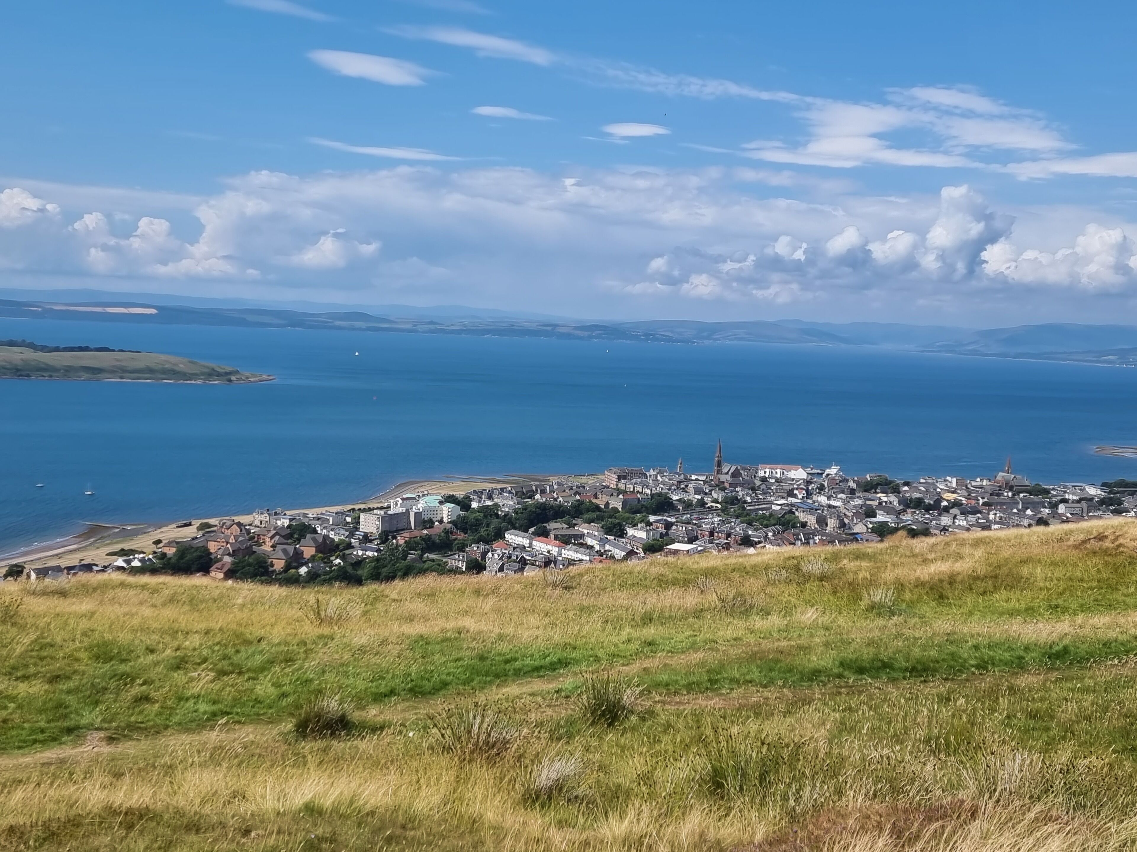 A coastal town with a prominent church spire, a beach, and a view of the sea.