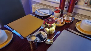 Une table à manger dressée avec des assiettes, des couverts, un chandelier et un centre de table décoratif.