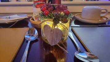 A table with a decorative centerpiece featuring a heart-shaped ornament, a glass vase with red berries, and a candle.