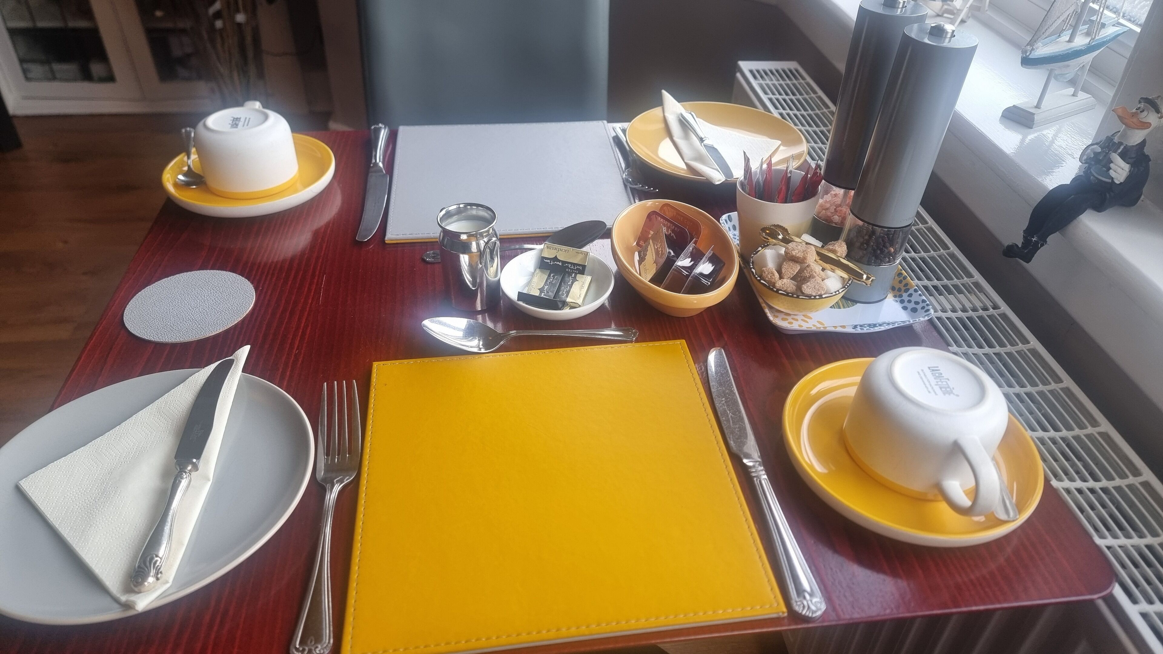 A dining table set with yellow and white tableware, including plates, bowls, and cups.