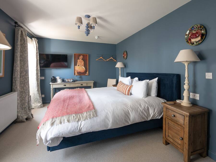 Une chambre à coucher avec un lit, des tables de chevet, un bureau et une chaise.