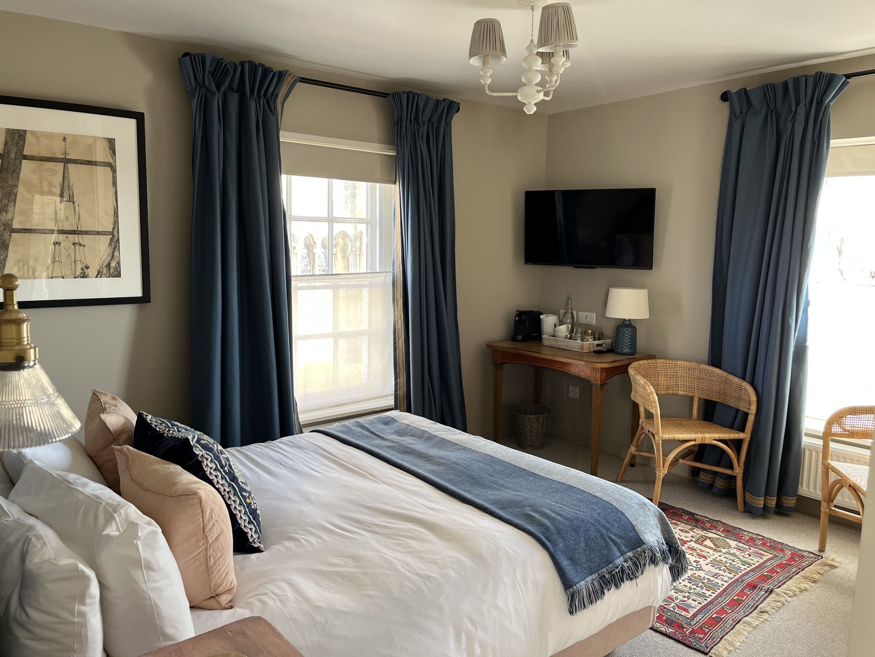 A hotel room with a bed, a desk, a chair, a television, and a window with curtains.