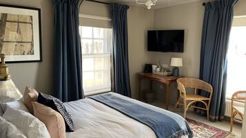 A hotel room with a bed, a desk, a chair, a television, and a window with curtains.