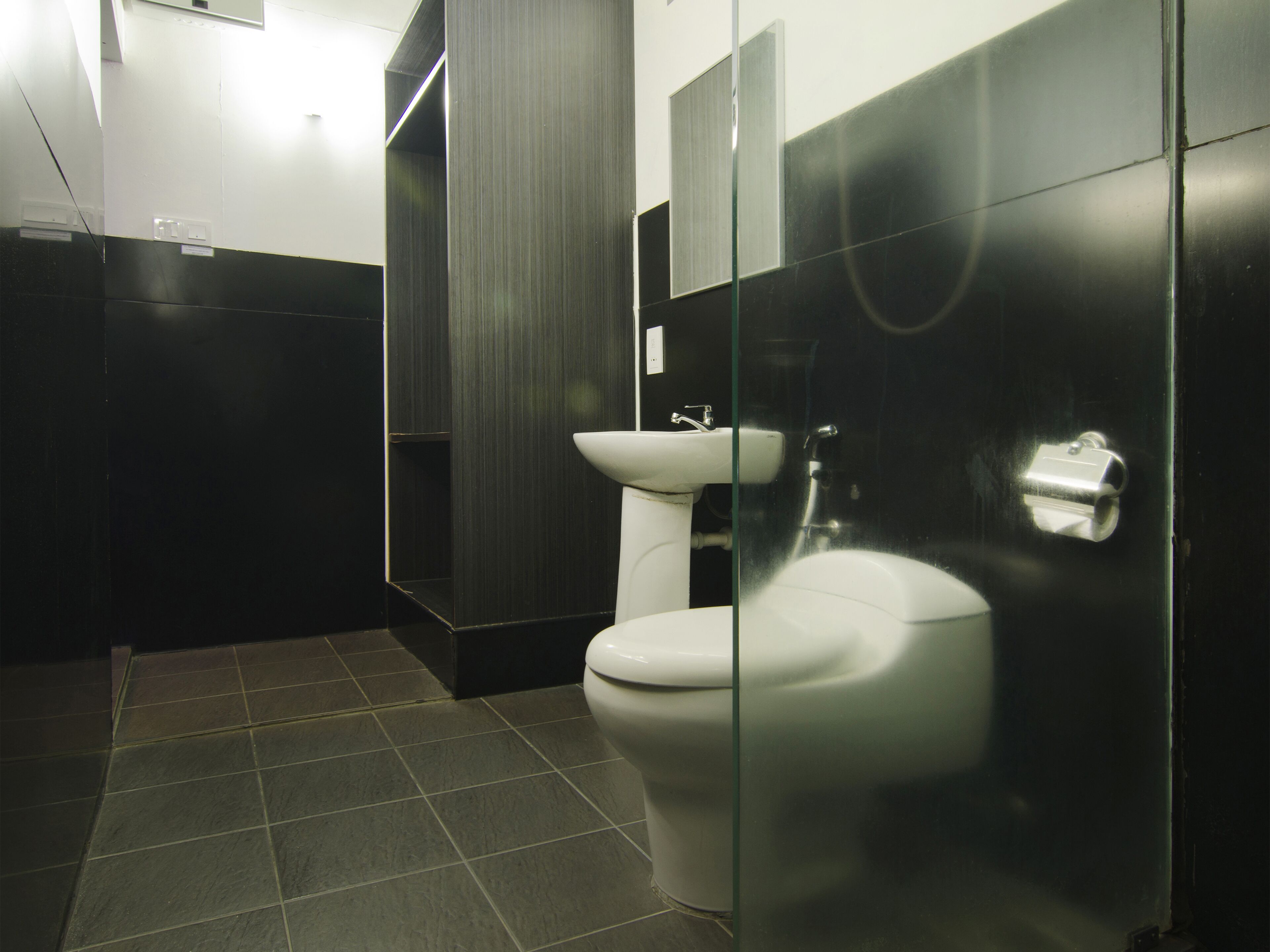 A modern bathroom with a toilet, sink, and glass partition.